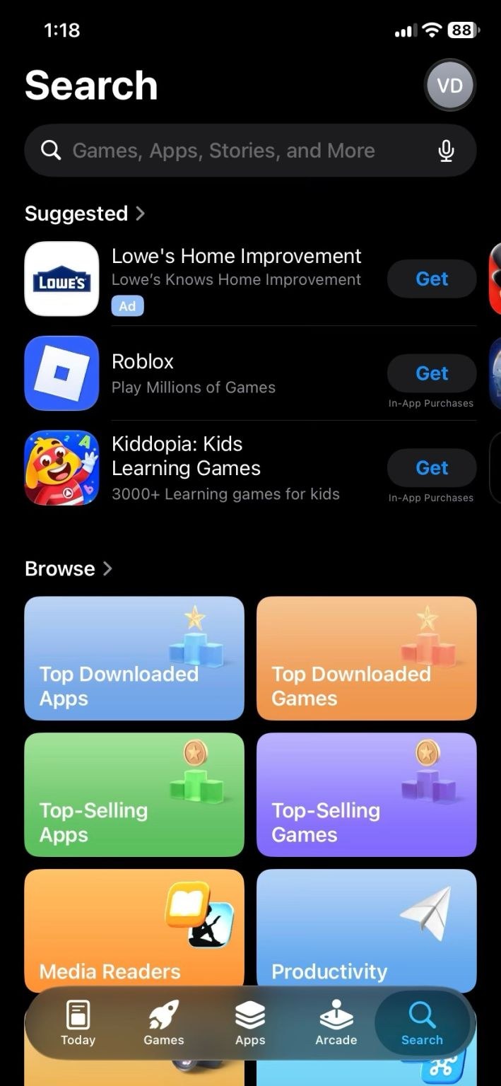 Liste des suggestions de l’onglet Recherche de l’App Store en mode sombre. Lowe's Home Improvement est signalé uniquement par une petite mention « Ad », sans fond coloré, au-dessus de Roblox et Kiddopia.